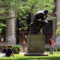 Thinker statue on upper campus with students sitting on the lawns nearby