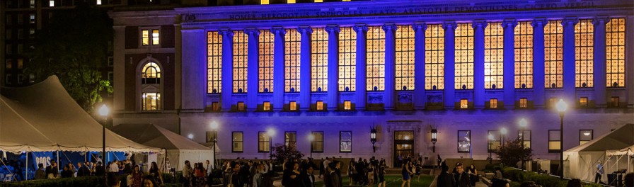 View of Butler Library and south lawns at night with party goers