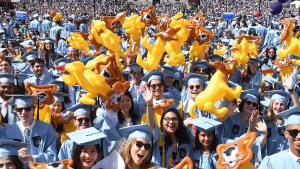 Students in academic regalia holding inflatable lions.