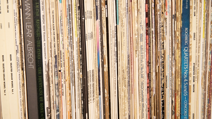 A shelf packed with records so all the spines are showing