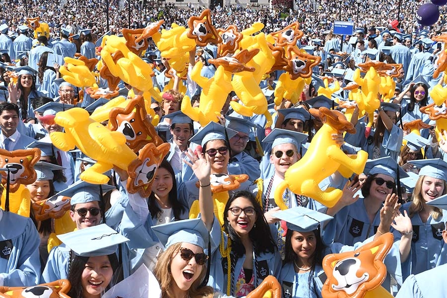 Students in regalia holding inflatable lions