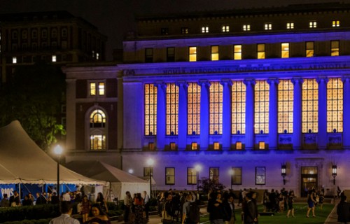 View of Butler Library and south lawns at night with party goers