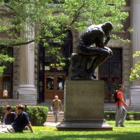 Thinker statue on upper campus with students sitting on the lawns nearby