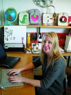 Claire Theobald ’88 at her desk. Peering over her shoulder are some Dante Beatrix products that feature the characters Percival the dragon, a Little Love, Wink, and Juju the ladybug.
