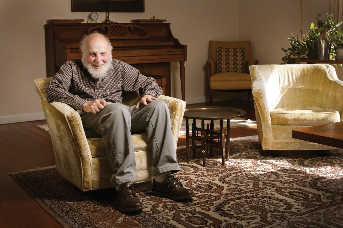 a man in an armchair, smiling