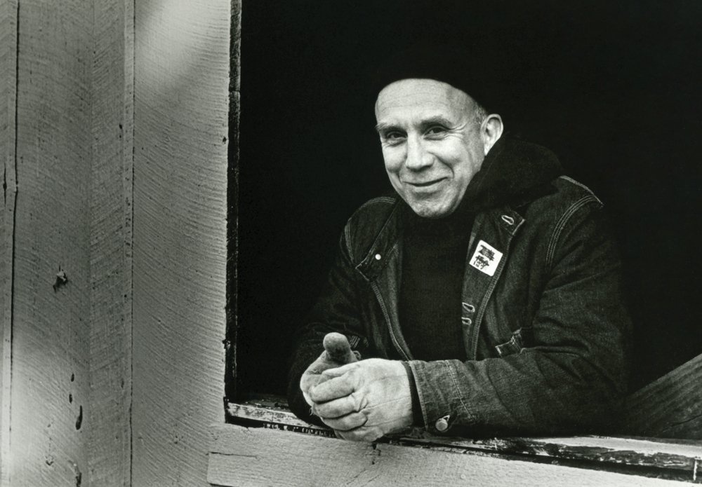 a smiling man leaning on an open windowsill