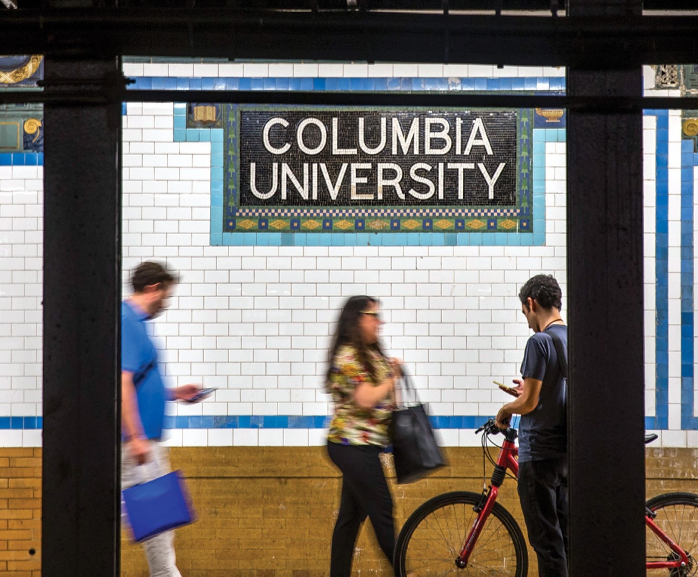 Subway platform for the number 1 train stop at Columbia University, showing a tiled wall containing a mosaic spelling "Columbia University".