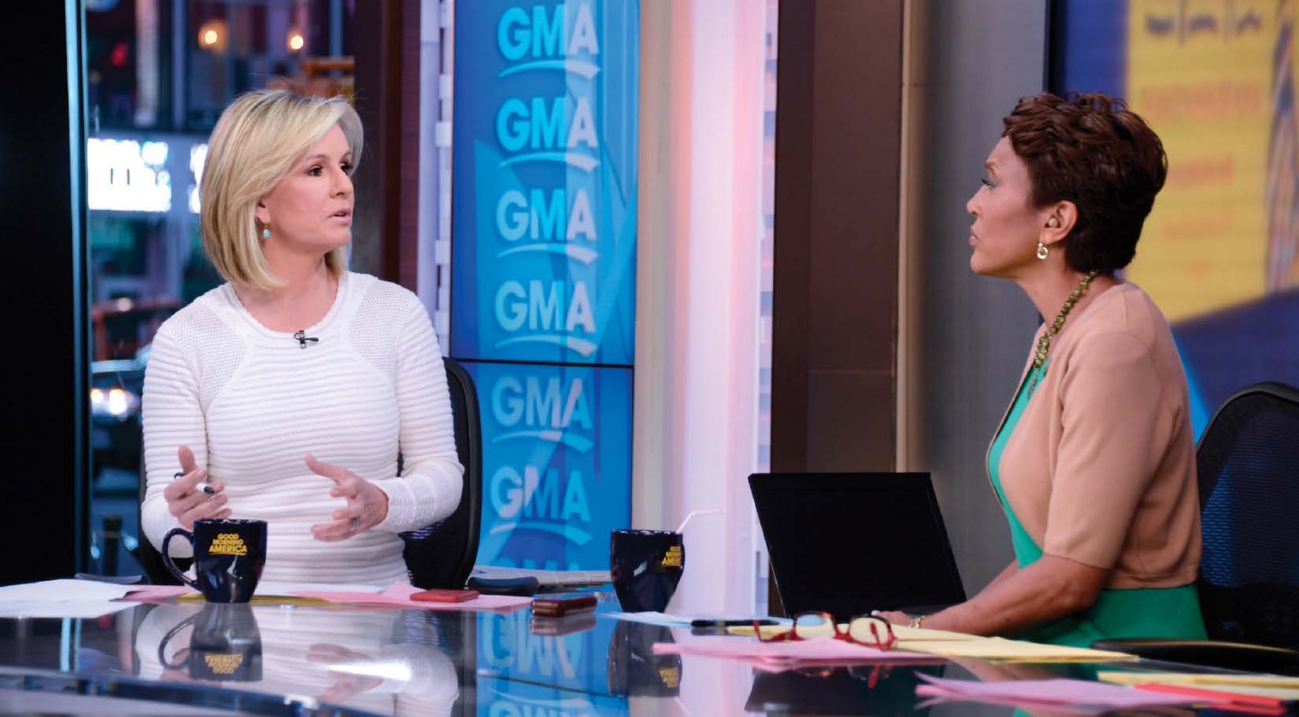 two women talking at a glass desk