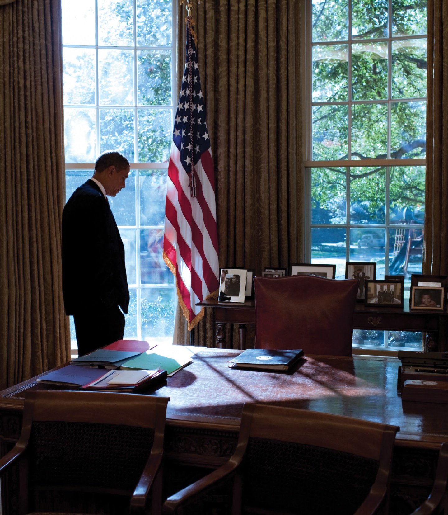 Barack Obama in the Oval Office, an American flag hanging nearby