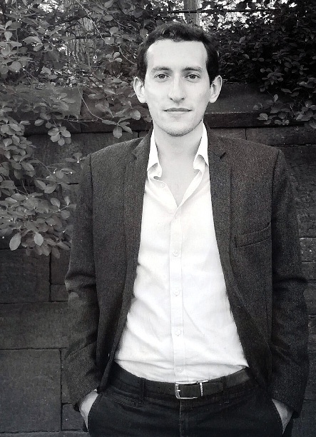 A black and white photo of a young man in an open-neck shirt