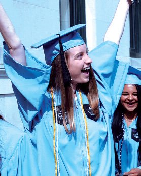 A graduating Columbia senior raises their arms in celebration.