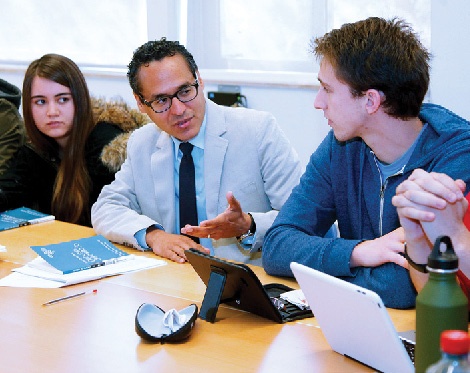 A man talking to students around a seminar table