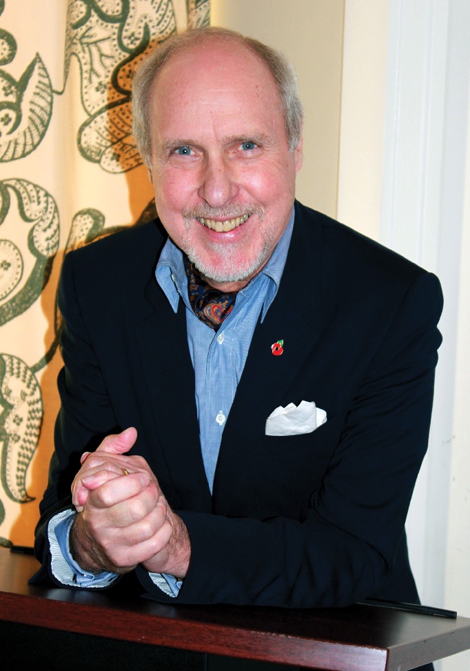 A smiling man in a blue shirt and dark jacket