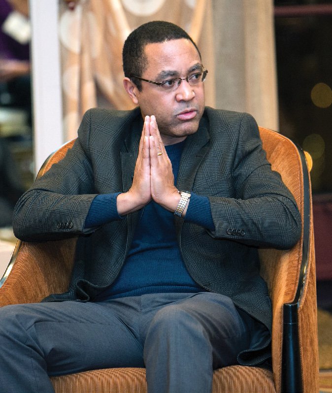 John McWhorter, seated in an armchair, glances to his left.