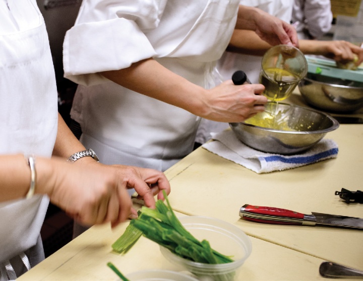 Three chefs prepare a dish.