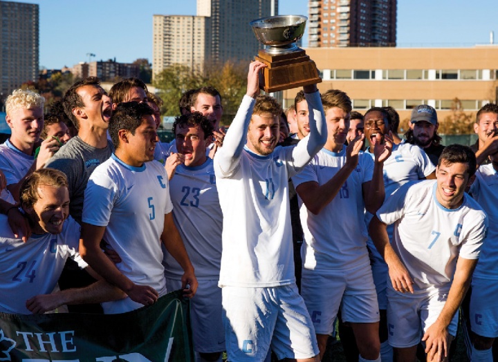 Young men in athletic gear lifting a championship cup