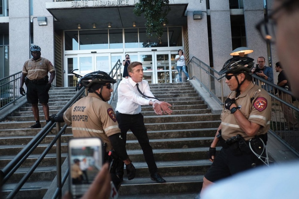 a man holding his hands out toward state troopers