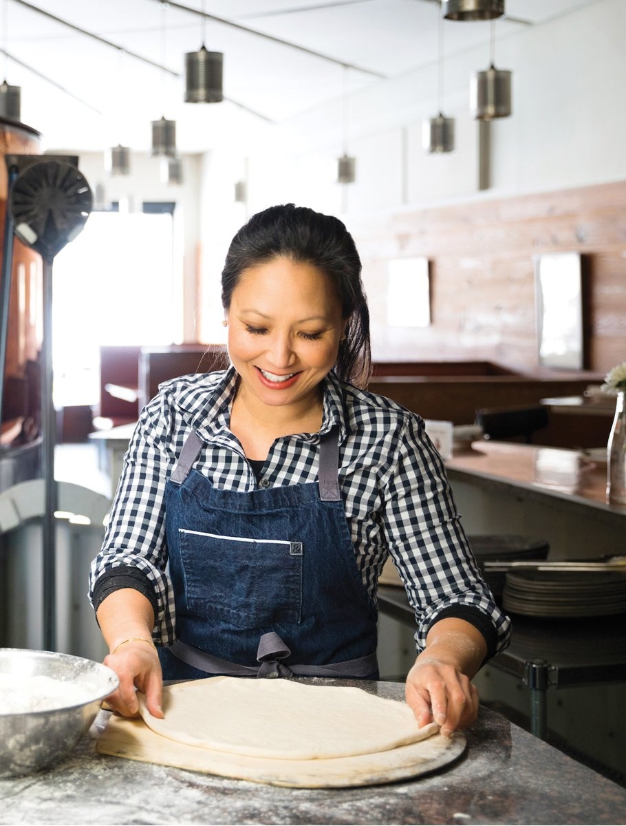 Woman in an apron working with pizza dough.