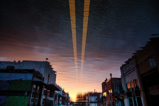 A photograph of the reflection of Fair Bluff, N.C., in stagnant floodwater after a succession of “once in a lifetime” hurricanes; September 24, 2018.