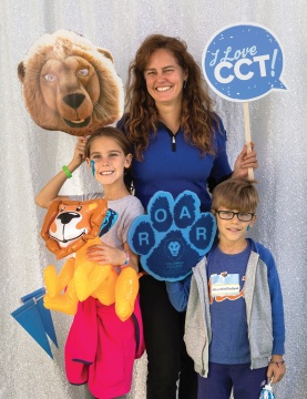 Woman with a boy and a girl, all smiling, each holding a sign depicting Roaree, the Columbia Lions Mascot. 